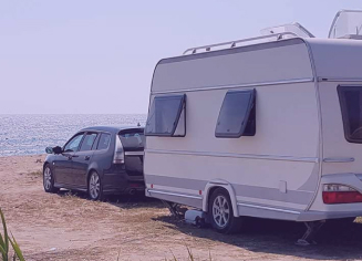 touring caravan hooked up to a car at the beach